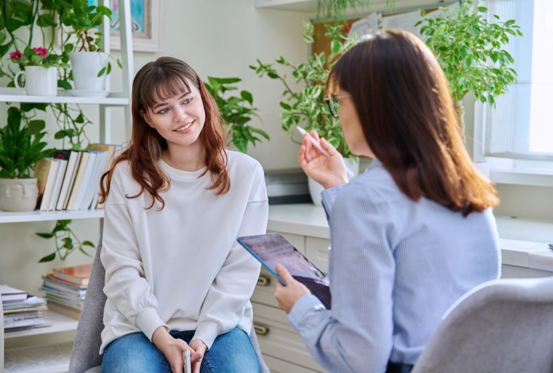 Two women are sitting in a room talking.