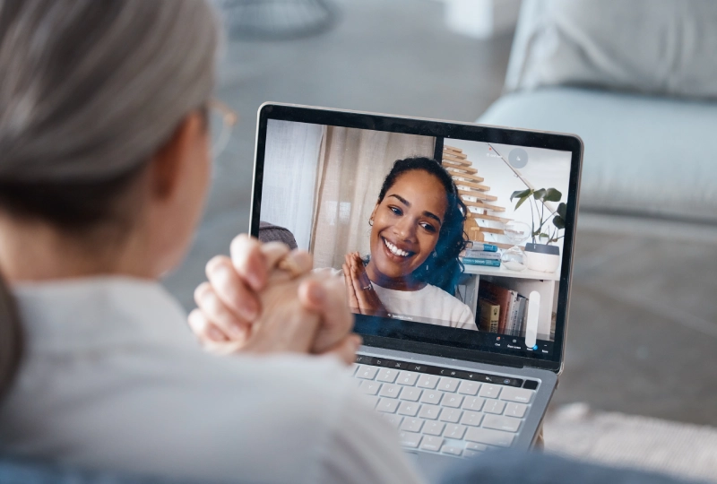 A woman is on her laptop and talking to someone.